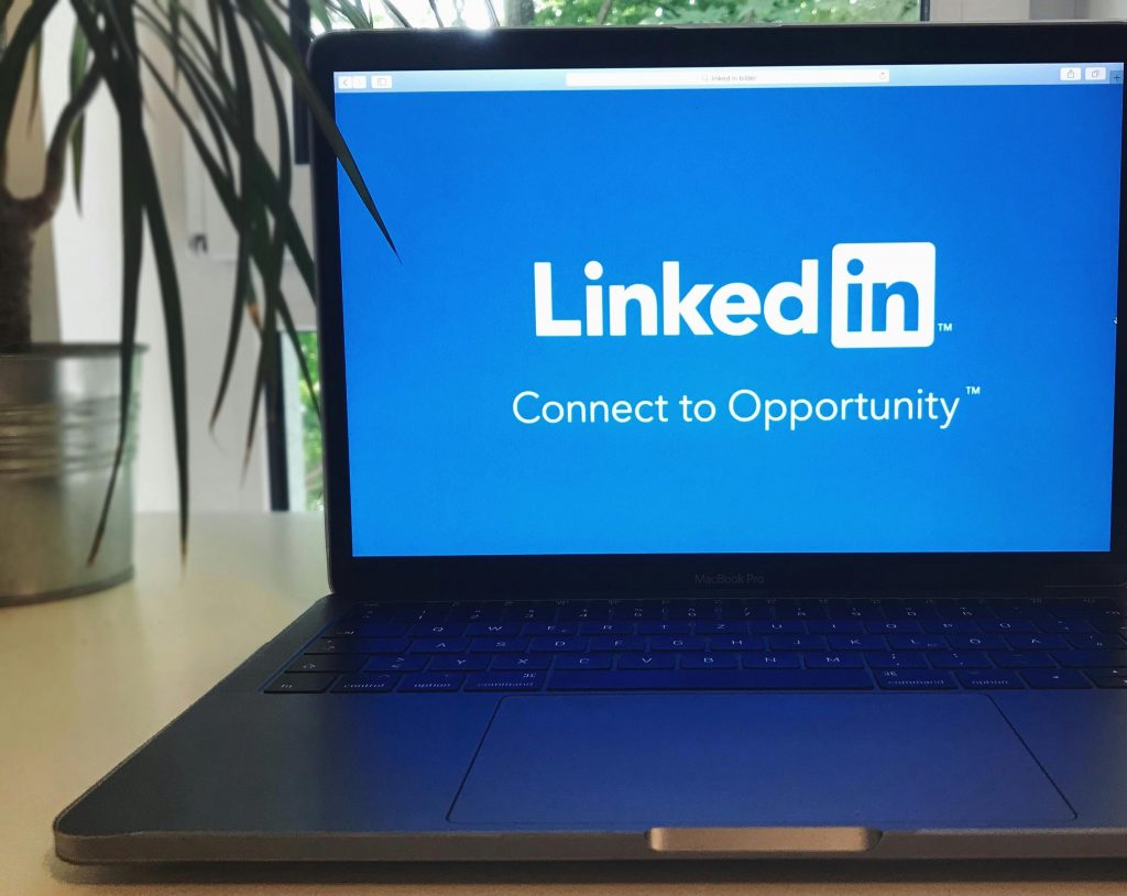 Comment utiliser LinkedIn pour décrocher un emploi rapidement ? A laptop screen displaying the LinkedIn logo with the text