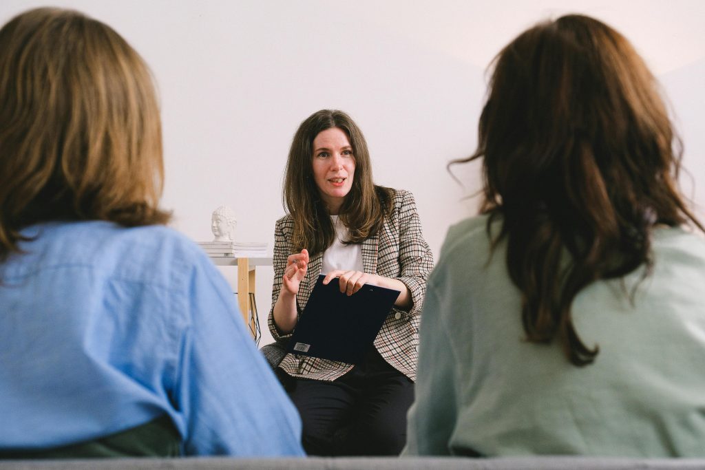 Comment se démarquer des autres candidats et décrocher l’emploi de vos rêves ? Therapist engaging in a conversation with two clients during a counseling session.