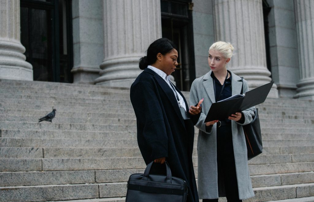 Two businesswomen discussing a document on city steps, showcasing teamwork and collaboration.