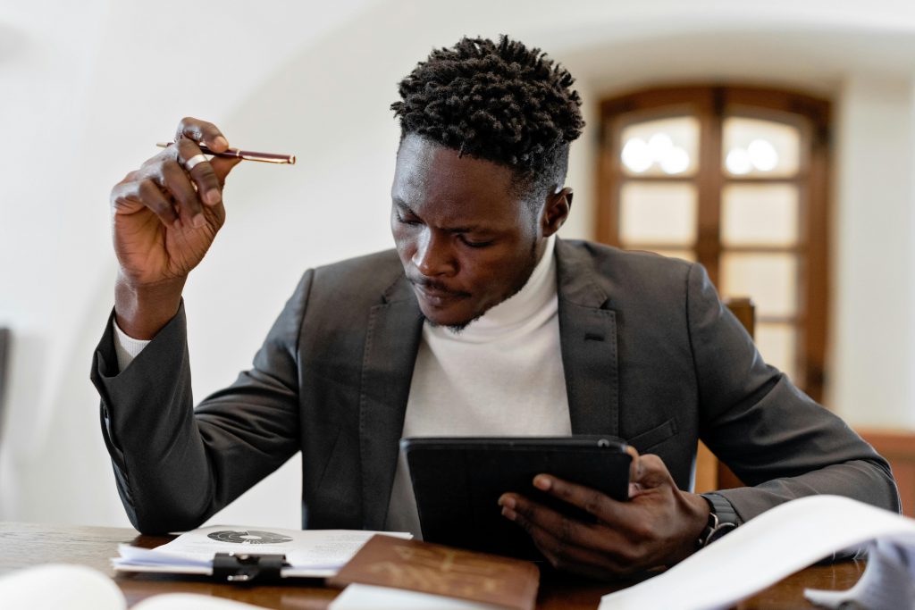 Confident businessman working on a tablet with documents in an office setting.