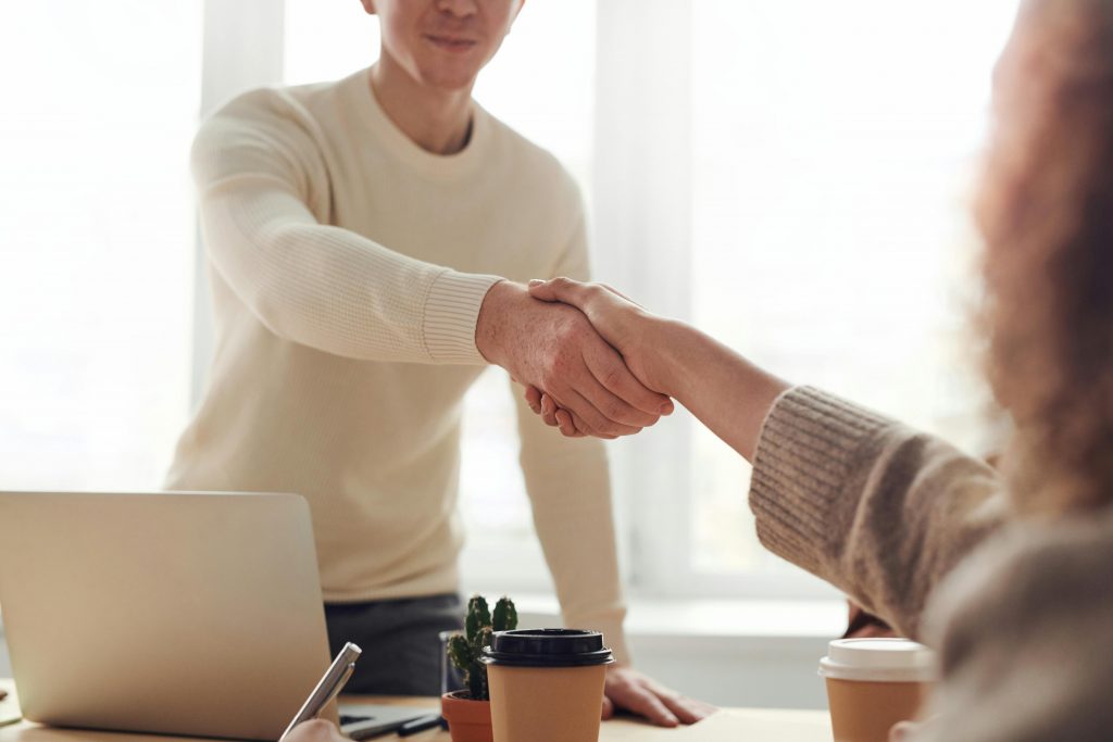 Comment passer à l’action pour trouver un travail en 3 jours ? Close-up of professionals shaking hands over coffee in a modern office.