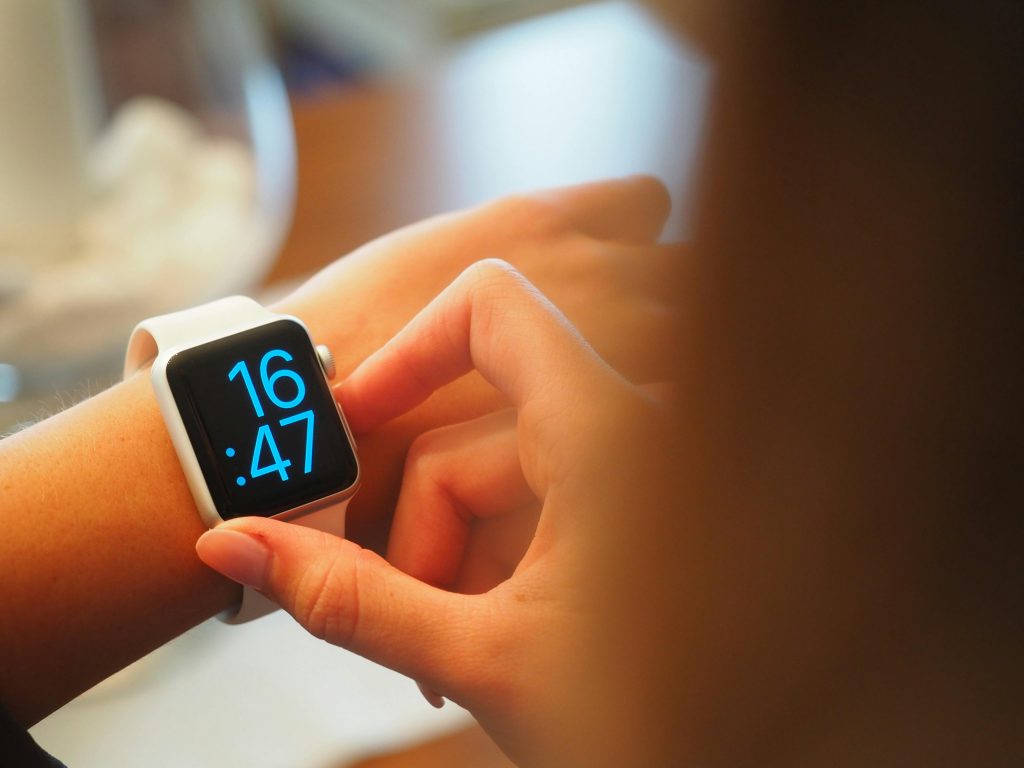 Gagner du temps au quotidien : 5 stratégies pour être plus efficace An individual operating a digital smartwatch displaying time with a blue interface.