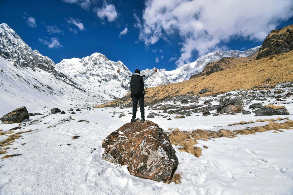Comment rendre un objectif SMART ? An inspiring view of a hiker with arms raised, surrounded by the snow-capped peaks of Jomsom, Nepal.