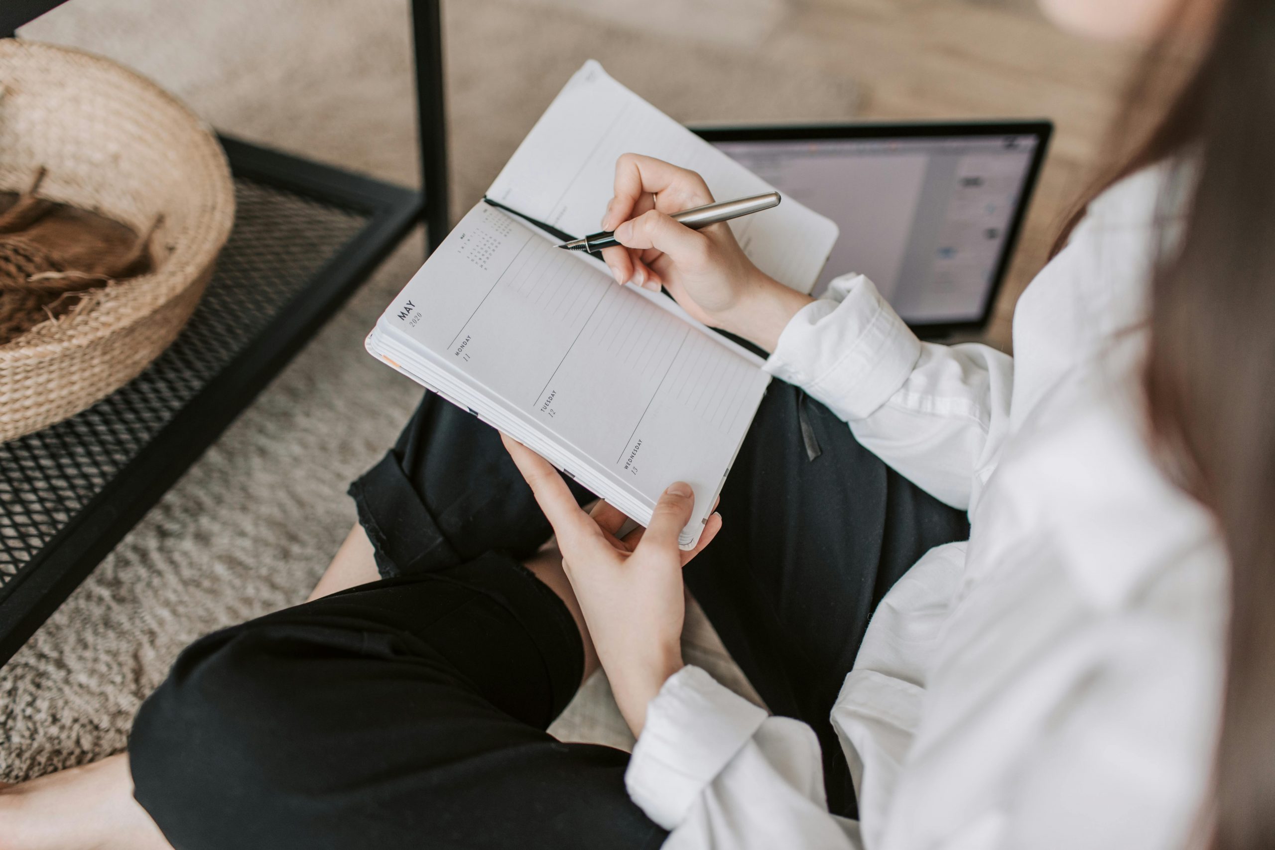 Gagner du temps au quotidien : 5 stratégies pour être plus efficace Side view of faceless woman in casual clothes taking notes on notepad while sitting in lotus pose on floor in modern apartment during daytime