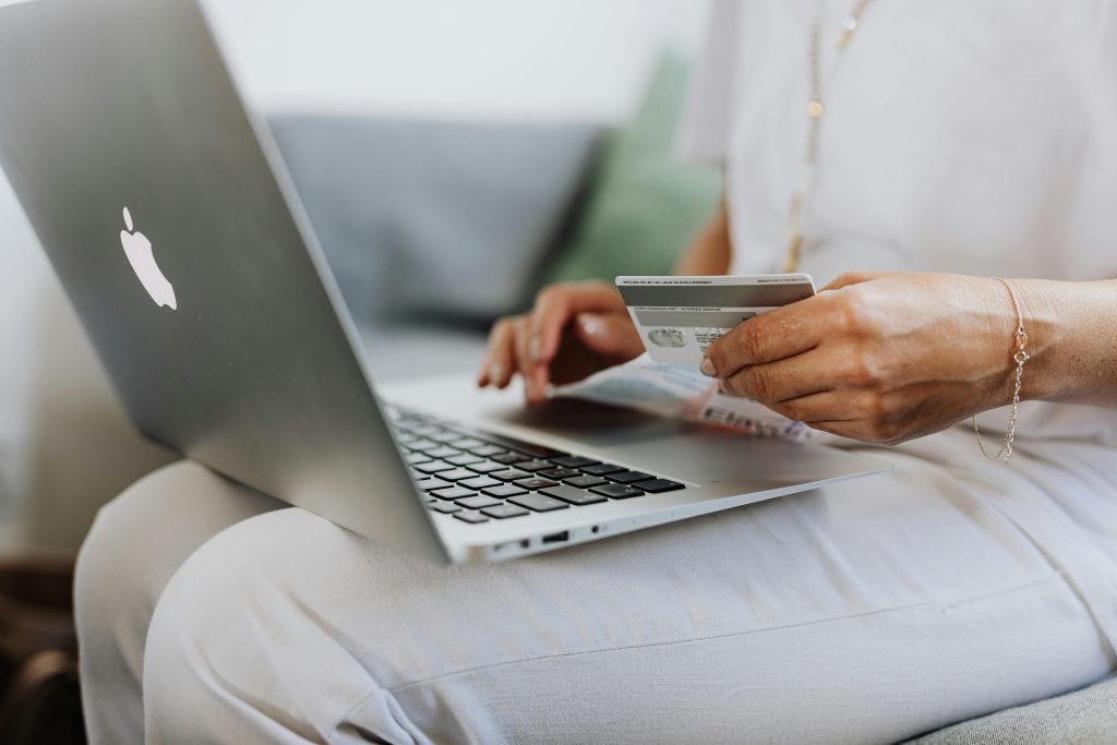 Dropshipping, e-commerce ou freelance : quel business choisir ? Close-up of a person holding a credit card while shopping online using a laptop at home.