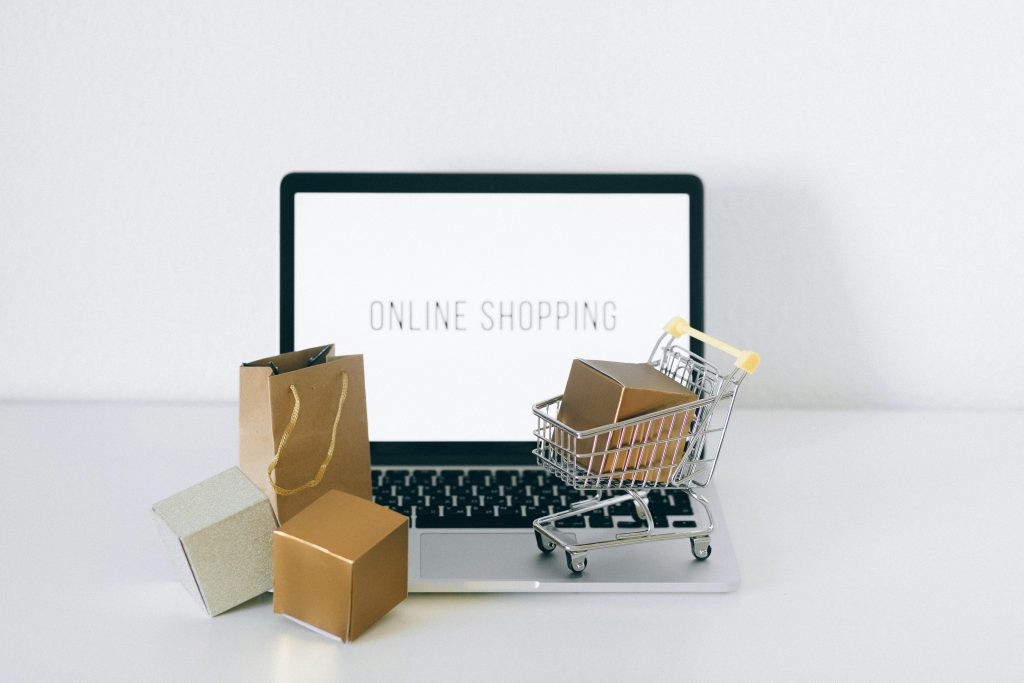 Dropshipping, e-commerce ou freelance : quel business choisir ? Laptop displaying online shopping with boxes and cart, representing ecommerce.