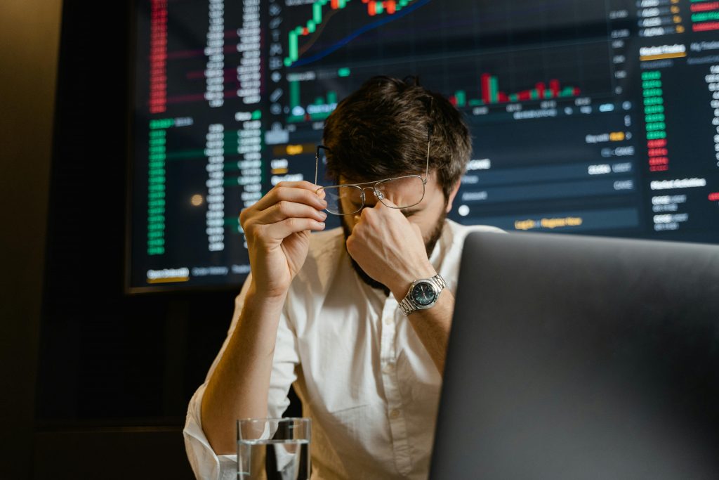 Les erreurs financières les plus fréquentes chez les débutants A stressed man looks at stock market data on his computer screen in an office setting.
