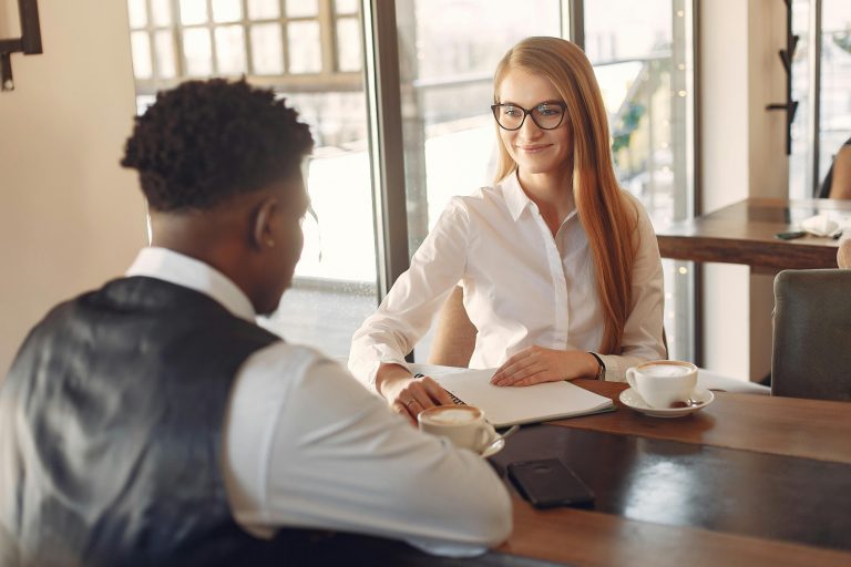 Blogs Two professionals engaged in a friendly business meeting in a stylish office setting.