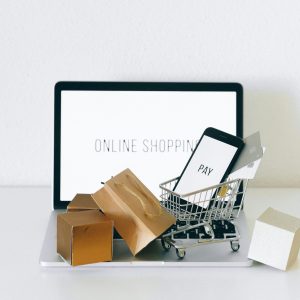 Display of online shopping theme with mini cart and payment devices on laptop.