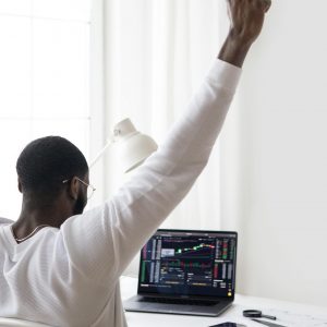 A man celebrates a successful stock market trade while sitting at his desk.